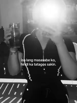 A black and white image shows a person holding a glass of dark liquid and a phone causing a bright white glare over the face. Text overlayed reads in Filipino.