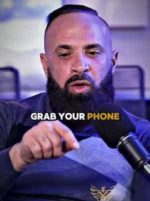 A man in a navy blue shirt with text overlay, pointing with his index finger. Background is blurred, but appears to be an office setting.