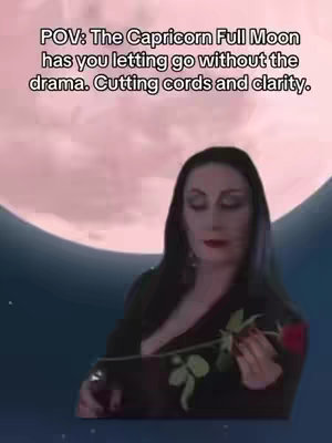 The image features Morticia Addams from the Addams Family holding a red rose and scissors in front of a backdrop of a pinkish moon and starry sky. Text overlayed on the image reads 'POV: The Capricorn Full Moon has you letting go without the drama. Cutting cords and clarity.'