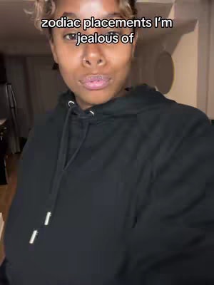 A medium shot features a person with short, light-colored hair and wearing a black hoodie. The person is looking at the camera, with text overlayed on the image. The background is dimly lit, suggesting an indoor setting.