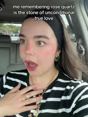 A woman with wide eyes and an open mouth reacts dramatically inside a vehicle. She wears a black headband, a striped black and white shirt, and gold jewelry. The text 'me remembering rose quartz is the stone of unconditional true love' is at the top of the frame.