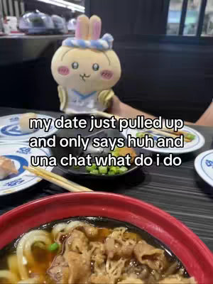 The image shows a plush toy of a yellow bunny wearing a white and blue outfit holding a plate with sushi on it, a small bowl of greens, and some chopsticks. In the foreground, there is a bowl of what appears to be udon noodles with meat in a red bowl. The text overlay in the image says 'my date just pulled up and only says huh and una chat what do i do.'