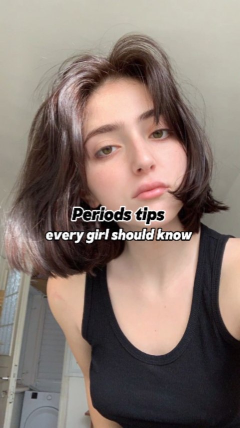 A selfie-style shot featuring a young woman with short, dark hair and a black tank top. Text overlay in white font indicates the video's focus. The woman has a neutral expression, with a hint of a smile, and is looking directly at the camera.