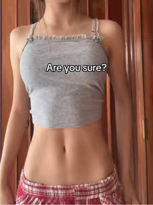 A medium shot of a person's torso and lower body. They are wearing a gray crop top and a red and white plaid mini skirt. The image is well-lit and focused on the person's midriff. The text overlay "Are you sure?" is present in white, centered above the crop top.