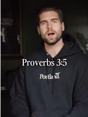 A man with a beard and dark hair wearing a black hoodie with white text is in front of a dark background with framed wall art on the left. Text overlay reads "Proverbs 3:5".