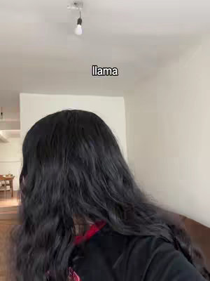 The video cover image shows a person with long, dark, wavy hair from behind. The person is wearing a dark top, and the background appears to be a brightly lit room with white walls and a light fixture hanging from the ceiling.