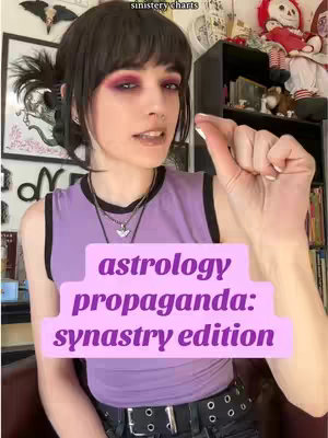 A person with dark hair and a purple top is holding up a hand with a small space between their thumb and forefinger. The person has burgundy eye makeup and a necklace with a triangle pendant. Overlayed is a pink rectangle with the text 'astrology propaganda: synastry edition'. The background includes a shelf with various items.