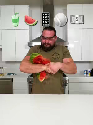 A man in a green shirt and safety glasses is holding a watermelon, which he has broken in half, in a kitchen. Floating above him are cartoon-style icons of a smoothie, a watermelon slice, a phone, a tennis ball, and money.