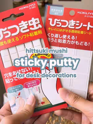 A person's hands holding two packages of 'Hittsuki Mushi' reusable sticky putty with English and Japanese text overlays. The packages are set against a blurred background, highlighting the product itself.