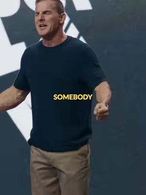 A man in a navy blue t-shirt and khaki pants gestures with his arms, looking upward with an expression of exertion or passion. The background is a gradient of dark gray. The hook text 'SOMEBODY' is in yellow.