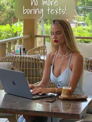 A woman with a fair complexion sits at a table outdoors, working on a laptop. She has long, blonde hair, red lipstick, and is wearing a light blue dress. A drink with ice and a straw sits beside the laptop. The text overlay says 'no more boring texts!'