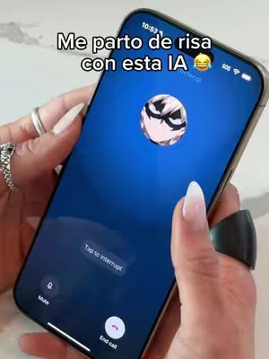 A person is holding a smartphone, displaying a video call interface. The phone screen has a blue background with a circular profile picture in the center, featuring a cartoon character. The person's hands, adorned with rings and long fingernails, are visible against a neutral surface, possibly a countertop. Text overlays appear at the top, while call control buttons are at the bottom of the screen.