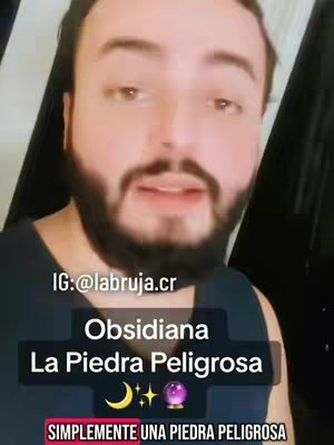 A man with a beard and short hair is centered in the frame. He is in front of a dark backdrop. Below him, there's an overlay with the text "Obsidiana La Piedra Peligrosa" in white, outlined with a black border. Symbols including a crescent moon, stars, and a crystal ball are displayed in the center. Further down, there's the text "SIMPLEMENTE UNA PIEDRA PELIGROSA". The image has a mobile video aspect ratio.
