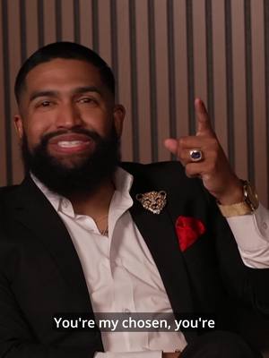 The cover image features a well-dressed man, seated and pointing upwards with one finger. He's wearing a suit with a crisp white shirt, a pocket square, and a decorative pin. A gold watch and a ring are visible. The background shows vertically striped wallpaper. Below the man is a text overlay.