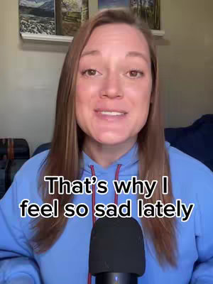 A front-facing shot of a woman with long brown hair in a blue hoodie. She is speaking into a microphone. Text is overlaid on the image.