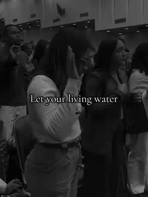 A black and white photo shows a crowded room, likely a church or auditorium, with people facing forward. A woman in the foreground, wearing a white shirt, has her hands raised near her face, and the text overlayed 'Let your living water'. The image is likely used for a Christian or worship themed video.