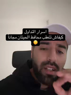 A man with a beard wearing a black hoodie and a white hat is shown, the background isn't very visible, so it seems to be inside his house. The image has a text overlay with Arabic script enclosed in a black box.