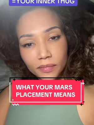 A woman with light skin and dark wavy hair is centered in the frame. The top of the image shows a blurred and slightly overexposed background. The woman has a neutral expression and is looking at the camera. A rectangular text box in the middle of the frame reads: 'WHAT YOUR MARS PLACEMENT MEANS'. The text is in white against a vivid red background, which is outlined with a black stroke. Black cross-shaped markings are visible at each corner of the rectangle, and the background color makes the text contrast against it. She is wearing a light green top.