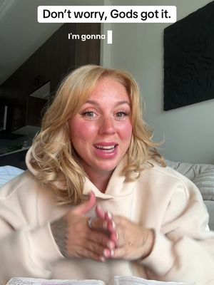 A selfie-style video cover featuring a blonde woman smiling and speaking. Text overlays are placed above her head. The background shows hints of a modern living space with a dark abstract art piece.