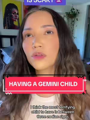 A woman with long brown hair looks up, with text overlays in red and white at the bottom and top, against a background of a living room, with art on the wall, a plant detail, and the woman is the primary focus, appearing in a selfie perspective.