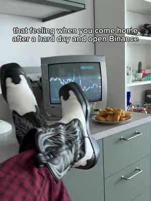 A person's legs and feet are propped up in front of an old television screen on a kitchen counter. The person is wearing cowboy boots. A plate of food sits on the counter near the television, and the screen displays a graph.