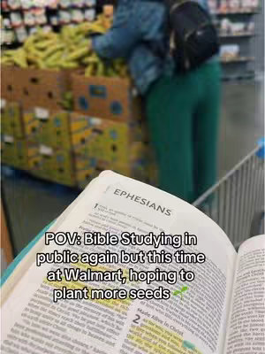 The image is a self-shot with a focus on an open Bible. The page is marked with highlights and text. The foreground shows the open book, while the background is blurred, featuring a Walmart setting with boxes of bananas and the legs of another person. The color scheme includes greens, yellows, and whites, with the book text and highlights drawing the eye.