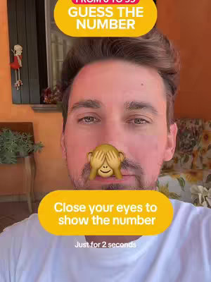 A selfie-style shot with a man's face centered. He is wearing a white t-shirt. A monkey-face emoji covers his mouth. There are two yellow rounded rectangles with text: one at the top says 'FROM 0 TO 99 GUESS THE NUMBER' and one at the bottom says 'Close your eyes to show the number Just for 2 seconds'. The background includes glimpses of a patio with plants and warm-toned orange walls.