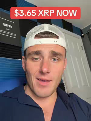 A selfie-style shot featuring a young man with fair skin wearing a white baseball cap and a dark blue collared shirt. He is against a backdrop with dark acoustic panels and a blue and black patterned surface. A red banner across the top of the image reads '$3.65 XRP NOW.' The man looks towards the camera with a slightly concerned expression.