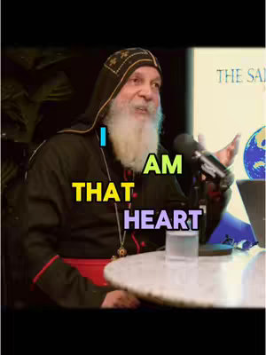 An image of a man in religious attire speaking into a microphone. The text overlay says 'I AM THAT HEART'.