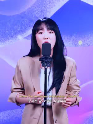 A woman with long black hair stands in front of a microphone, singing. She wears a beige blazer over a white top. Behind her, a purple and blue gradient background provides a soft-focus backdrop. Text overlays appear below her, presenting lyrics in both English and Korean.
