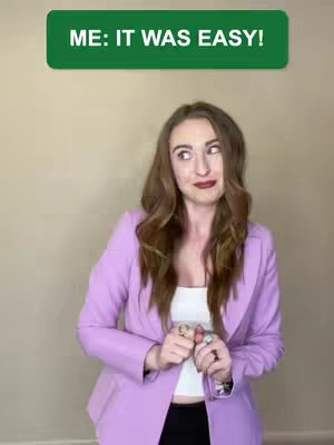 A woman with long brown hair and a slight smile is looking upward and to her left. She's wearing a white top, a light purple blazer, and rings on her fingers. A green rectangle with white text, the video's hook, is at the top of the image.