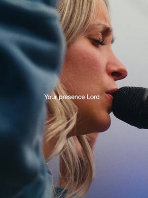 A close-up shot features a blonde woman in profile, with soft lighting highlighting her face as she holds a microphone. Text overlays on the bottom that says "Your presence Lord".