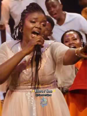 The cover image depicts a woman singing into a microphone, surrounded by a choir. She is the focal point, dressed in a light-colored gown with a sequined bodice, her mouth open as she sings. Behind her, other members of the choir are visible, some also singing with their mouths open. The overall lighting is bright, and the composition suggests a performance.