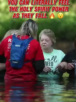A group of people, waist-deep in water, are the focus, with an overlay of text above. The central figure appears to be assisting a woman in a light green shirt while an additional person is on the left. The water's surface is clear.