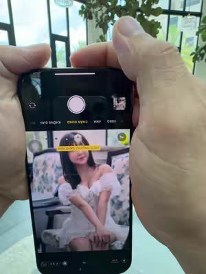 A person's hands hold a phone displaying the Meitu app and a partially captured photo of a woman. The phone's camera interface and the woman's image are visible on the screen.