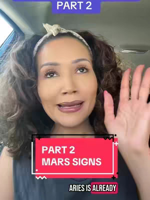 A woman is seated in what appears to be a car, facing the camera. Above her, a rectangular banner reads 'PART 2' in white text on a purple background. Below, a red square contains the words 'PART 2' over 'MARS SIGNS' in white, and further down, 'ARIES IS ALREADY', also in white, are visible. She's wearing a headband and her right hand is up, as if gesturing, with her palm facing forward.
