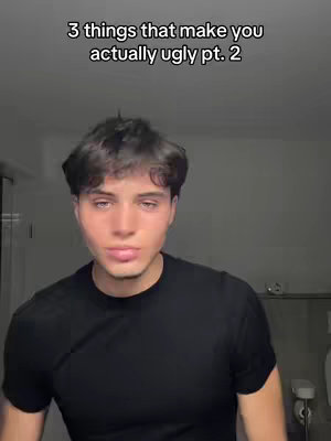A young man stands in front of a neutral background, framed from the chest up. The man has short dark hair and is wearing a black t-shirt. The text overlay says '3 things that make you actually ugly pt. 2'. The lighting appears to be soft.
