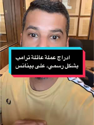 A man with short dark hair and a yellow shirt is centered in the frame. A text box in navy with white and red lettering displays Arabic text. The background suggests an office setting with framed photos on a wall.
