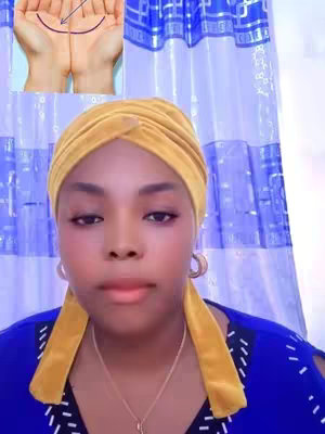 A selfie-style image with a woman facing the camera. She is wearing a gold head wrap, gold hoop earrings, a necklace, and a blue top. Behind her is a blue and white patterned curtain, and in the top left corner, there's a small inset image of two hands with palmistry lines. The woman has a fair complexion and is looking directly at the viewer.