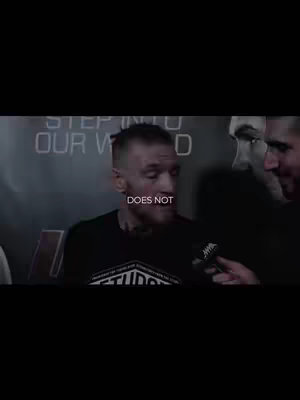 The cover image shows a man, likely a celebrity or public figure, in a dark setting. He's wearing a black t-shirt. The man is being interviewed and is holding or being held by a microphone. The text overlay says "DOES NOT". The background is muted, making the man the focus.