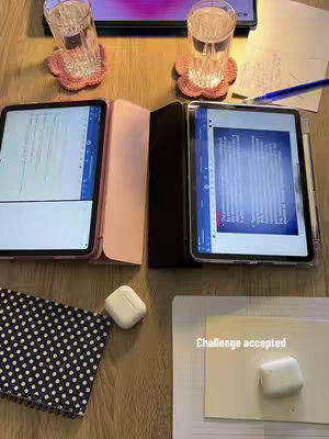 The cover image shows a desk setup for studying. Two tablets are side-by-side, each displaying documents. Glasses of water sit on crocheted coasters behind the tablets. A polka-dot notebook and AirPods are also on the desk. The overall color scheme is warm, with wooden desk and soft lighting.