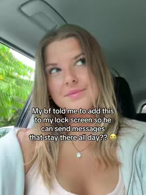A young woman is seated in a car, looking slightly off-camera with a thoughtful expression. The image is brightly lit, with the car's interior visible and foliage seen through the window. The text overlay in the centre appears to be white text on the image.