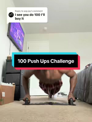 A person is doing a push-up on a push-up board, with the camera facing them. They are wearing shorts. In the background, there is a bed, a TV, and a piece of furniture. A text overlay reads "100 Push Ups Challenge."