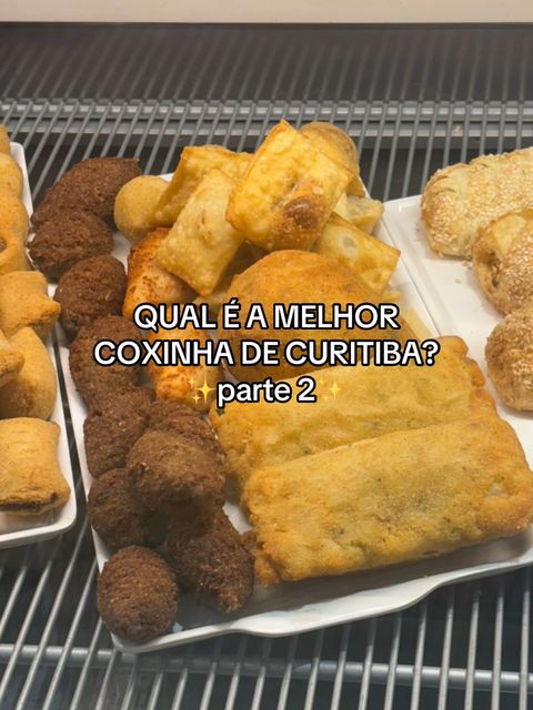 The cover image shows an assortment of fried food items, possibly snacks or appetizers, arranged on a white serving tray. The food consists mainly of golden-brown, breaded items, including what appear to be coxinhas, and other pastries. Text overlay at the image center reads 'QUAL É A MELHOR COXINHA DE CURITIBA? parte 2.' The background is simple, potentially of a food display environment.