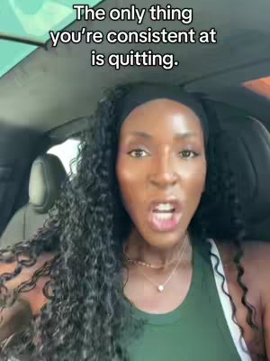 A woman with long curly hair is in a car and speaking directly to the camera. Her hair is black. She's wearing a black headband, a necklace with a small pendant, and a green top. The car's interior is visible, and there is text overlayed at the top of the screen.