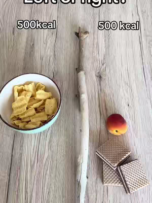 The image is composed of a wooden texture background. In the center, a long, thin tree branch stands vertically. To the left, a white bowl contains yellow, wavy chips. Above it, the text "500kcal" is displayed. To the right, there is a group of three square wafers stacked next to a peach. Above the wafers, another "500kcal" text is placed.