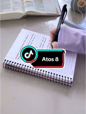 The image shows a notebook with notes and a person’s hand writing with a pen. A book lies open in the background. A TikTok branded overlay at the bottom includes text. The image has muted colors, with light tones on the surface.