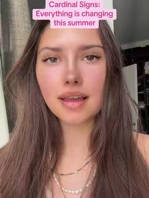 A young woman with long brown hair looks directly at the camera. A pink rectangular text overlay is at the top of her head. She is wearing a necklace. The background is slightly blurred.