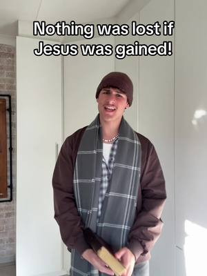 A young man wearing a beanie, scarf, and jacket stands against a light background, holding a book and smiling. Text is overlaid at the top of the image.