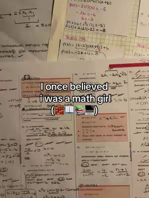The image is a close-up shot of a desk covered in papers filled with mathematical equations and notes. A text overlay states "I once believed i was a math girl" in white letters. Below it are several small emojis, including books. The layout suggests a study or academic environment.